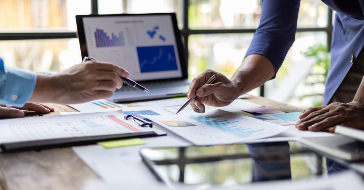 Two businessman discussing financial charts on laptop in office. Analyzing data. Strategizing. And planning for success. Teamwork and collaboration towards growth and success in business.